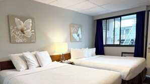 Ein Hotelzimmer mit zwei Betten, einem Nachttisch, einer Lampe und Wandkunst mit Schmetterlingen.
