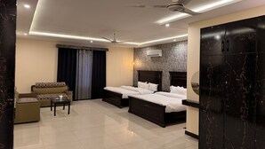 A modern hotel room with a large bed, a sofa, a coffee table, and a ceiling fan.