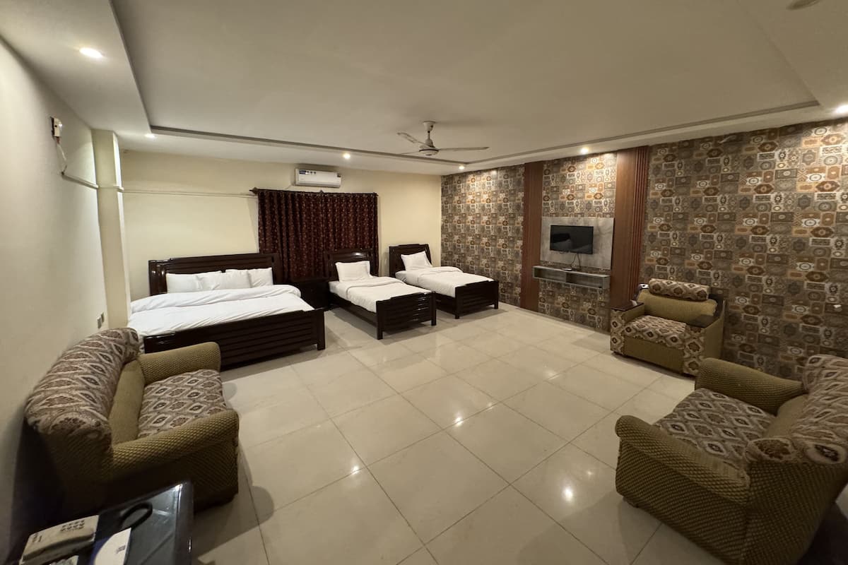 A hotel room with two beds, a TV, and patterned wallpaper.