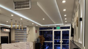 A hotel lobby with a marble reception desk, a fire extinguisher, and an exit sign.