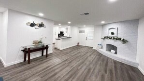 Un vaste espace de vie comprenant un coin salon avec cheminée, une table à manger et une cuisine en arrière-plan.