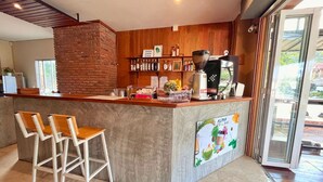 A cafe with a wooden counter, bar stools, a coffee machine, and a menu board. - ALPHA Hostel Cafe&Bar (Krabi)