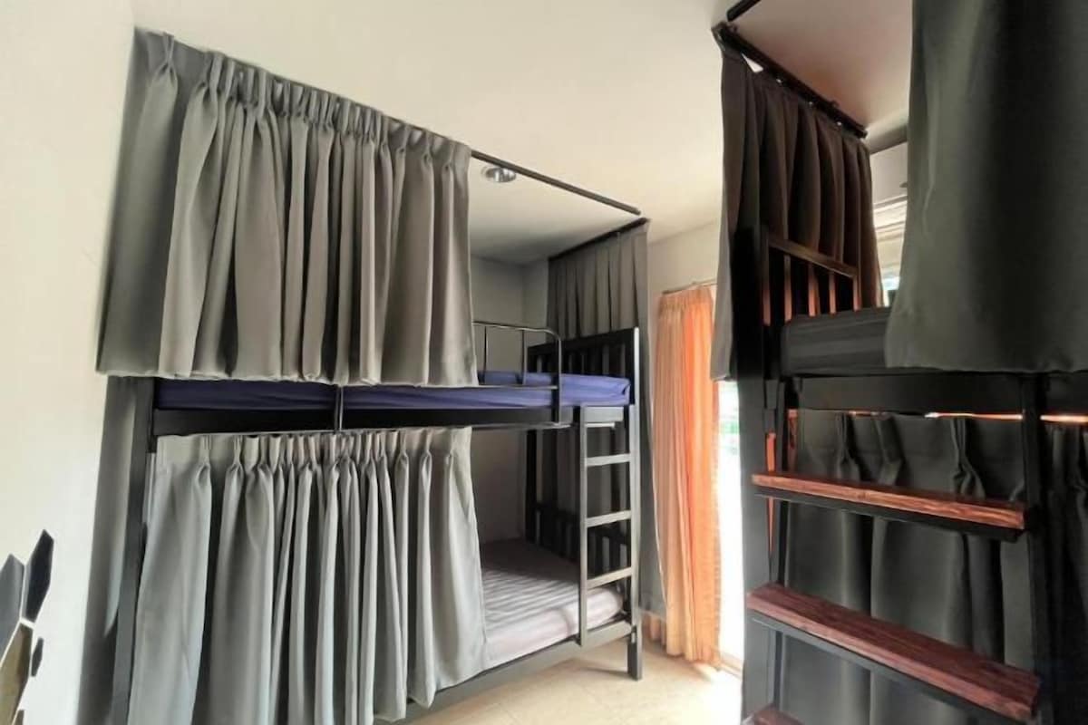 Une chambre avec un lit superposé, des rideaux, une échelle et une fenêtre.