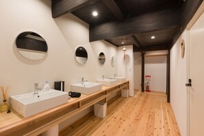 A modern bathroom with three sinks, wooden vanity, and multiple mirrors.