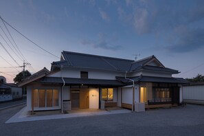 A traditional Japanese house with a tiled roof, wooden beams, and sliding doors.