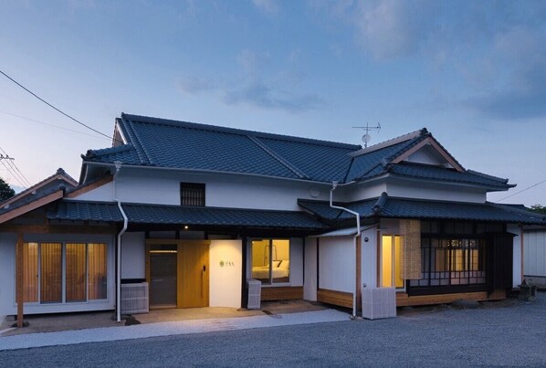 A traditional Japanese-style house with a tiled roof, a wooden door, and a small porch area.