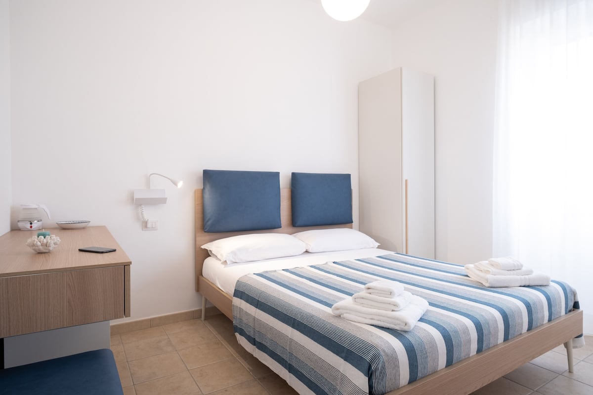 A neatly arranged bedroom with a bed, bedside table, and a wardrobe.
