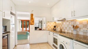 Une cuisine moderne avec des meubles blancs, un lave-linge Bosch et un plan de travail en granit.