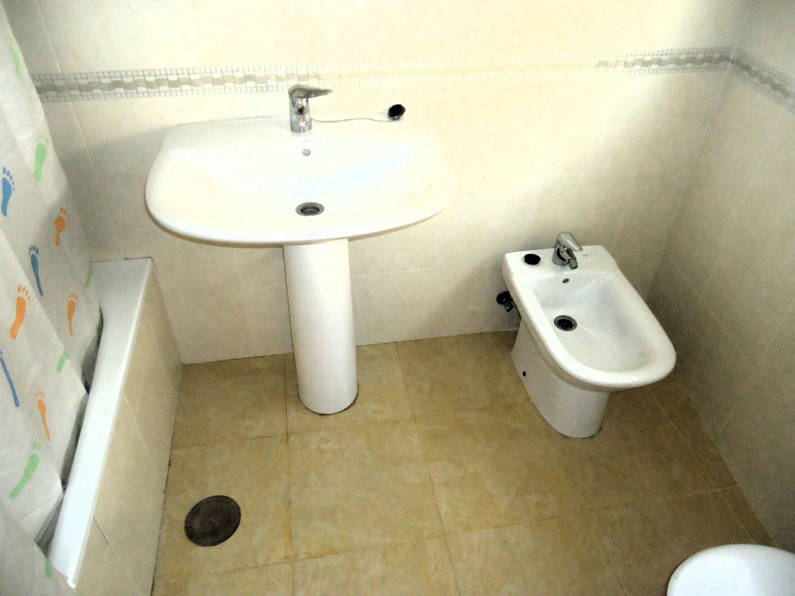 A bathroom with a pedestal sink, a bidet, and a toilet.