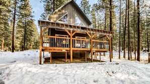 A wooden cabin with a balcony, surrounded by snow and tall pine trees. - Newly owned Cabin w/ private hot tub, A/C & covered deck - Dog Friendly! (Leavenworth)