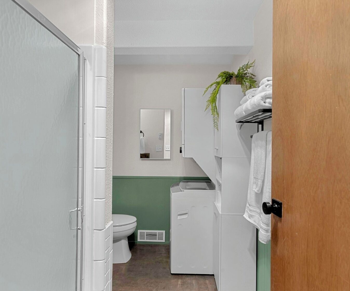 A compact bathroom with a toilet, a small sink, and a mirror.