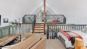 A loft bedroom with a wooden staircase, a bed with a plaid blanket, and a green cabinet. - Newly owned Cabin w/ private hot tub, A/C & covered deck - Dog Friendly! (Leavenworth)