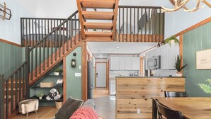 A spacious living area with a wooden staircase, a cozy seating area, and a kitchen with modern appliances. - Newly owned Cabin w/ private hot tub, A/C & covered deck - Dog Friendly! (Leavenworth)