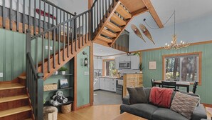 A spacious living area with a wooden staircase, a dining area, and a kitchen. - Newly owned Cabin w/ private hot tub, A/C & covered deck - Dog Friendly! (Leavenworth)