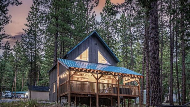 A cabin with a wooden deck, a metal roof, and a large window. - Newly owned Cabin w/ private hot tub, A/C & covered deck - Dog Friendly! (Leavenworth)