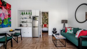 Um espaço compacto com cozinha compacta, área de refeições e sala de estar com sofá verde e mesa de centro.