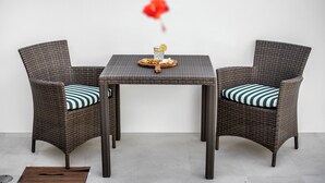 Conjunto de jantar de vime com duas cadeiras e uma mesa, incluindo um copo, um prato com comida e uma rodela de limão.