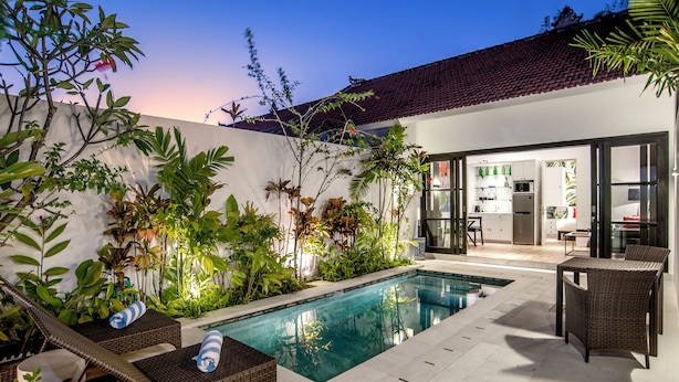 Uma área de piscina moderna ao ar livre, com espreguiçadeiras e um conjunto de jantar.