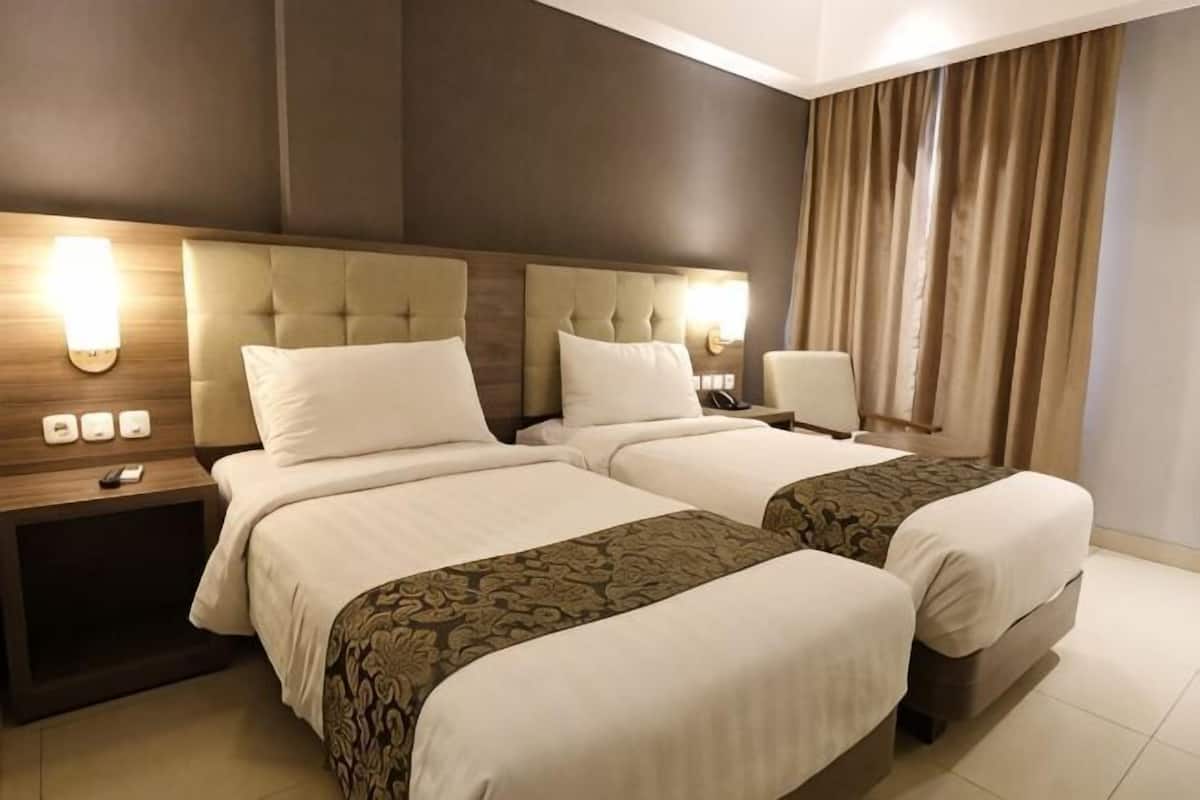 Une chambre dâhĂŽtel avec deux lits, une table de chevet, une lampe et une vue sur lâextĂ©rieur.