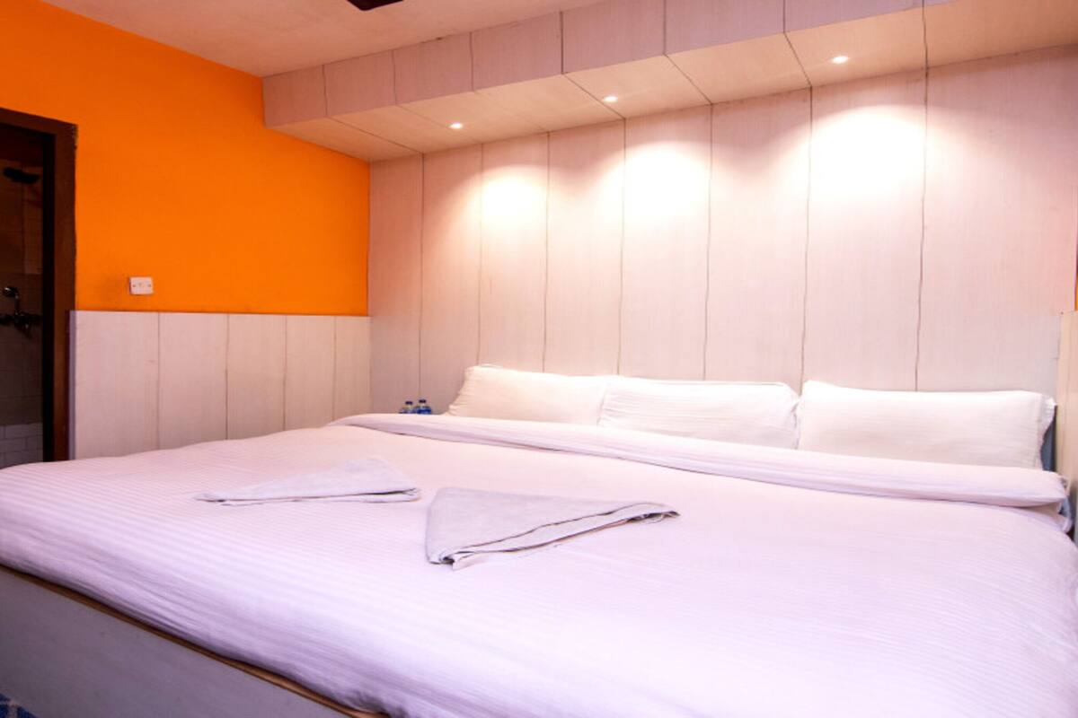 Une chambre d’hôtel avec un lit, une douche et un mur orange.