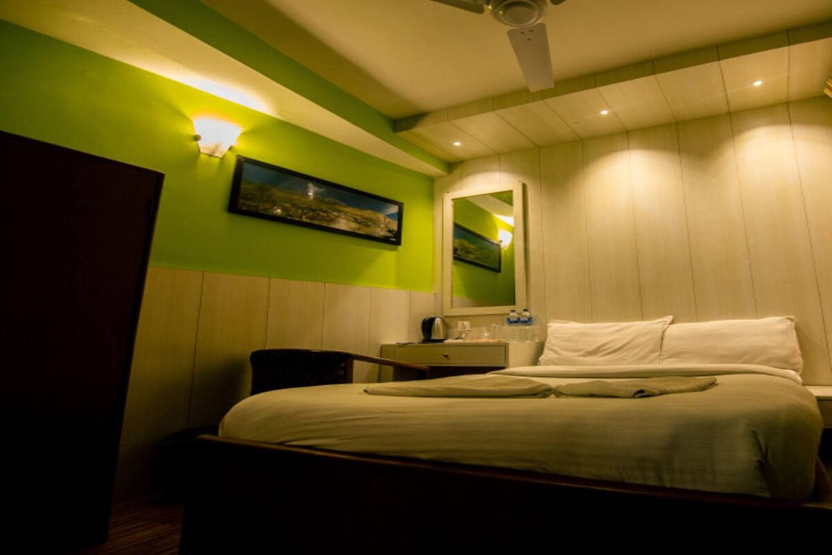 Une chambre d’hôtel avec un lit, une table de chevet et un miroir.