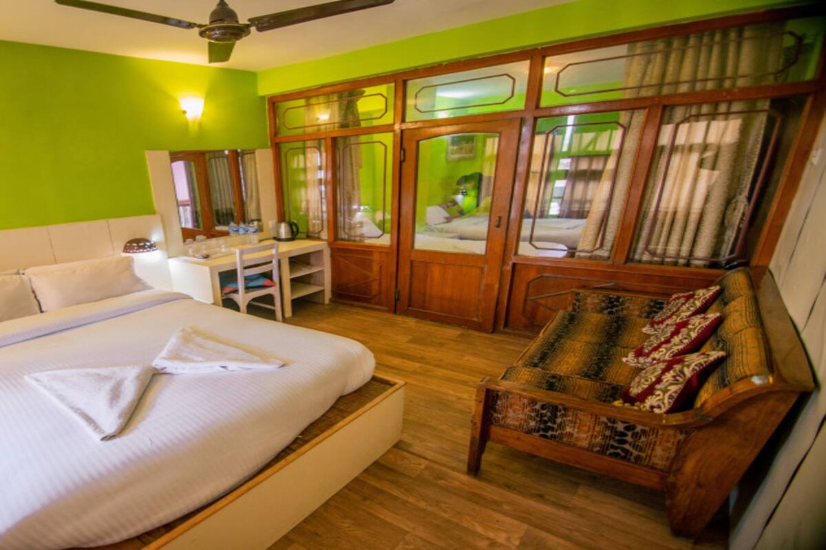 Une chambre d’hôtel avec un lit, un bureau, une chaise et une armoire.