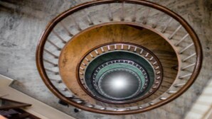 A spiral staircase with a wooden handrail and metal balusters. - MeroStay 180 Hotel EMO (Kathmandu)