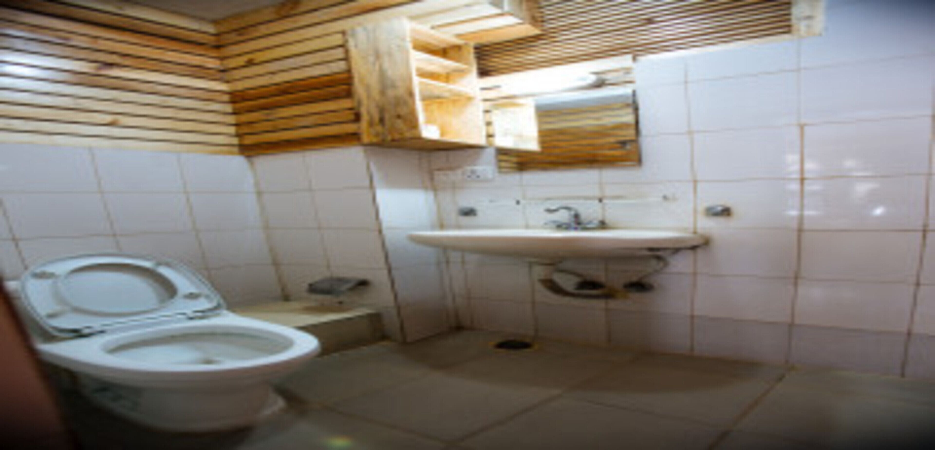 Een kleine badkamer met toilet, wastafel en houten lambrisering.