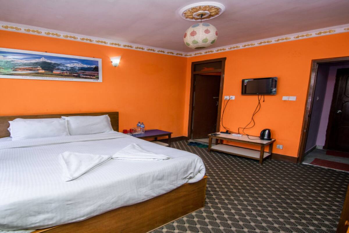 Une chambre d’hôtel avec un lit, un tableau au mur, une télévision et une porte.