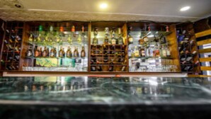 A bar with shelves of bottles and a mural on the wall. - MeroStay 180 Hotel EMO (Kathmandu)