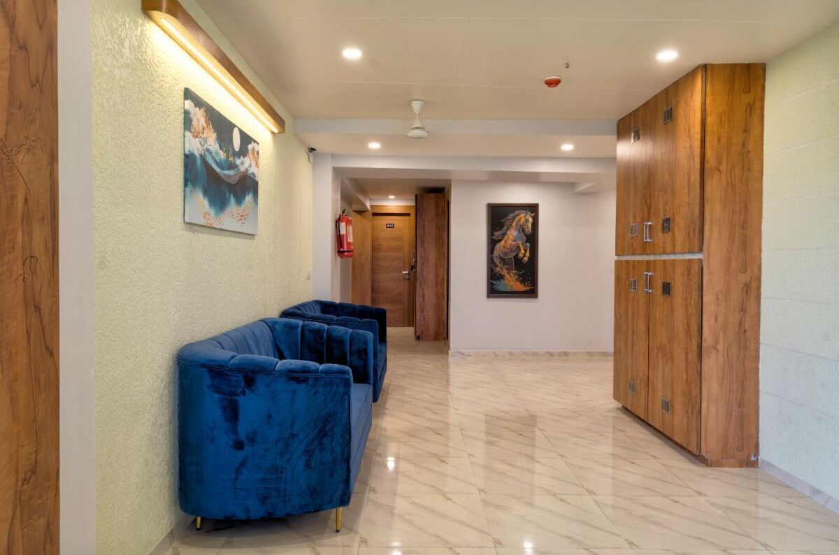 Un pasillo con un sofá azul, armarios de madera y obras de arte en las paredes.