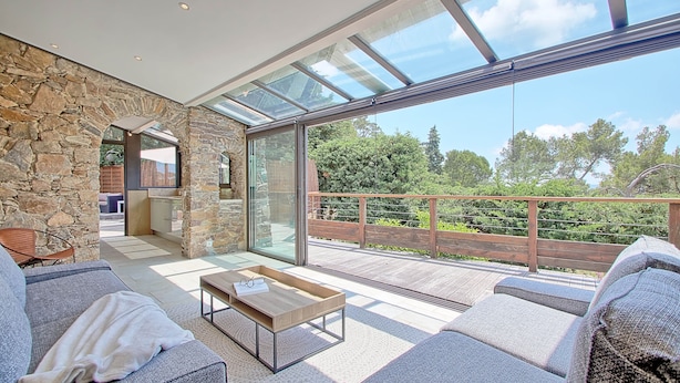 A modern interior with a stone wall, a glass door leading to a balcony, and a seating area with a coffee table.