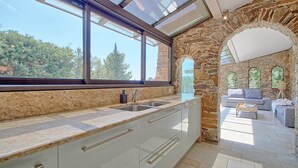 A modern kitchen with a large window, stone archway, and a cozy seating area with a sofa and coffee table.