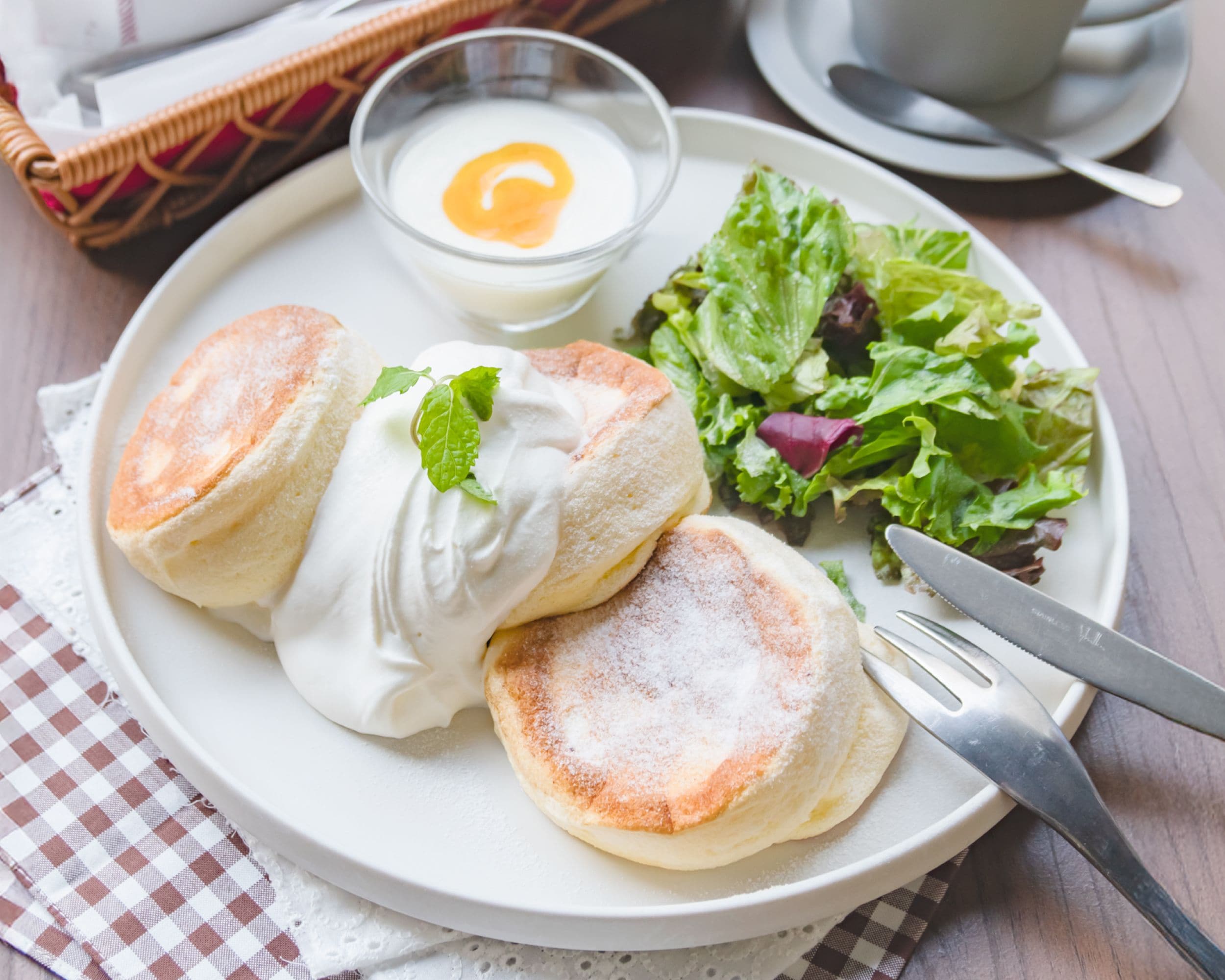 Une assiette de crêpes, une portion de salade et un petit bol d’œufs.