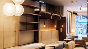 Un interior moderno con un mostrador de recepción curvo, zonas de estar e iluminación colgante.