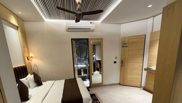 Quarto de hotel moderno com cama, mesa de centro de vidro, sofá, ventoinha no teto e guarda-roupa.