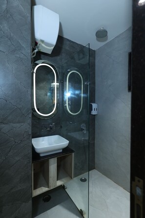 A modern bathroom with a glass-enclosed shower, a white sink, and two oval mirrors with built-in lighting. - Hotel sar kamla dham (Mathura)
