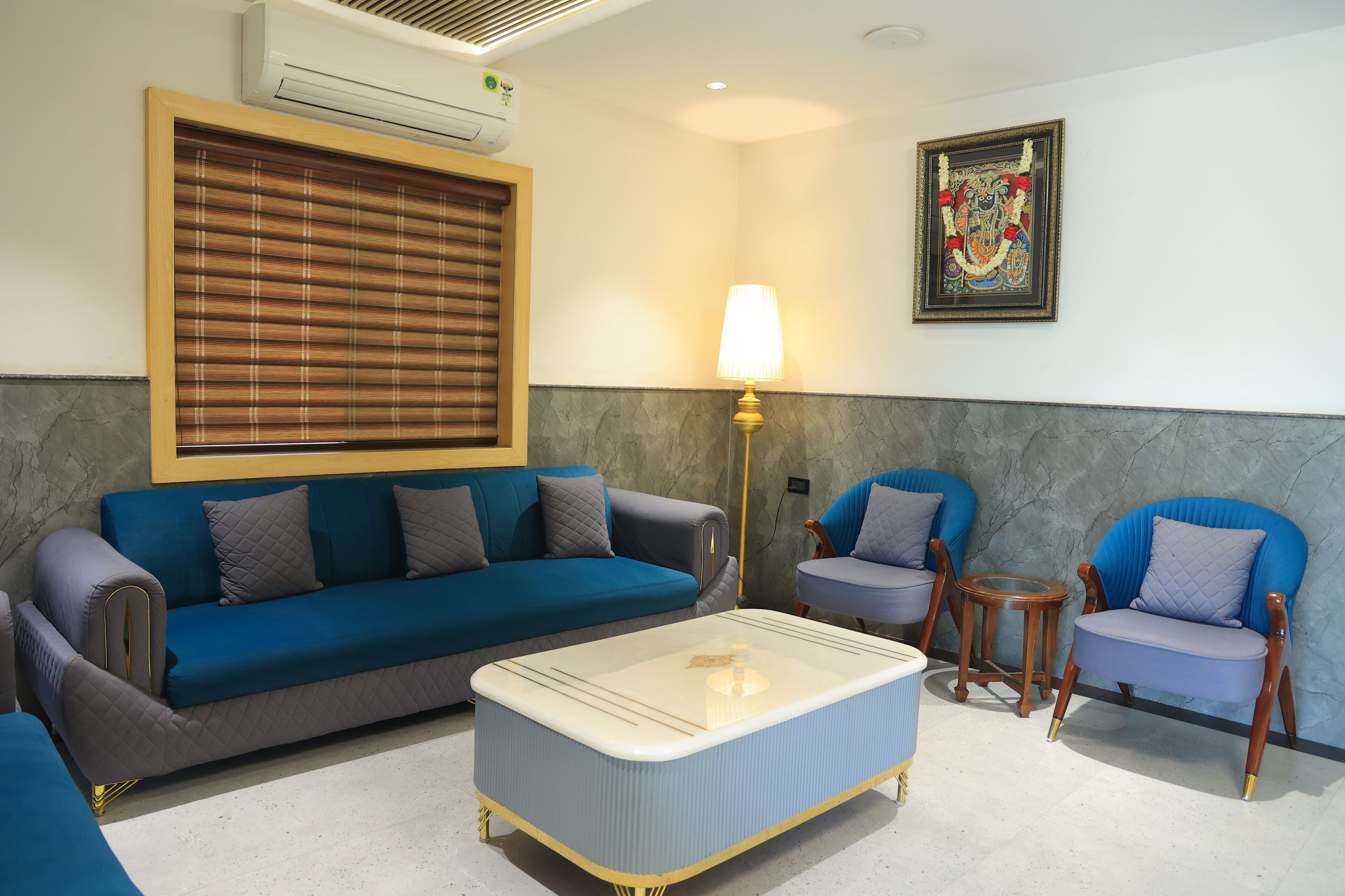 A living room with a blue sofa, a blue armchair, a small round table, and a floor lamp.