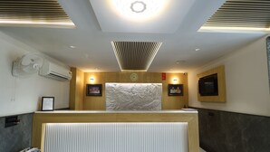 A reception desk with a clock, wall-mounted artwork, and a built-in fan. - Hotel sar kamla dham (Mathura)