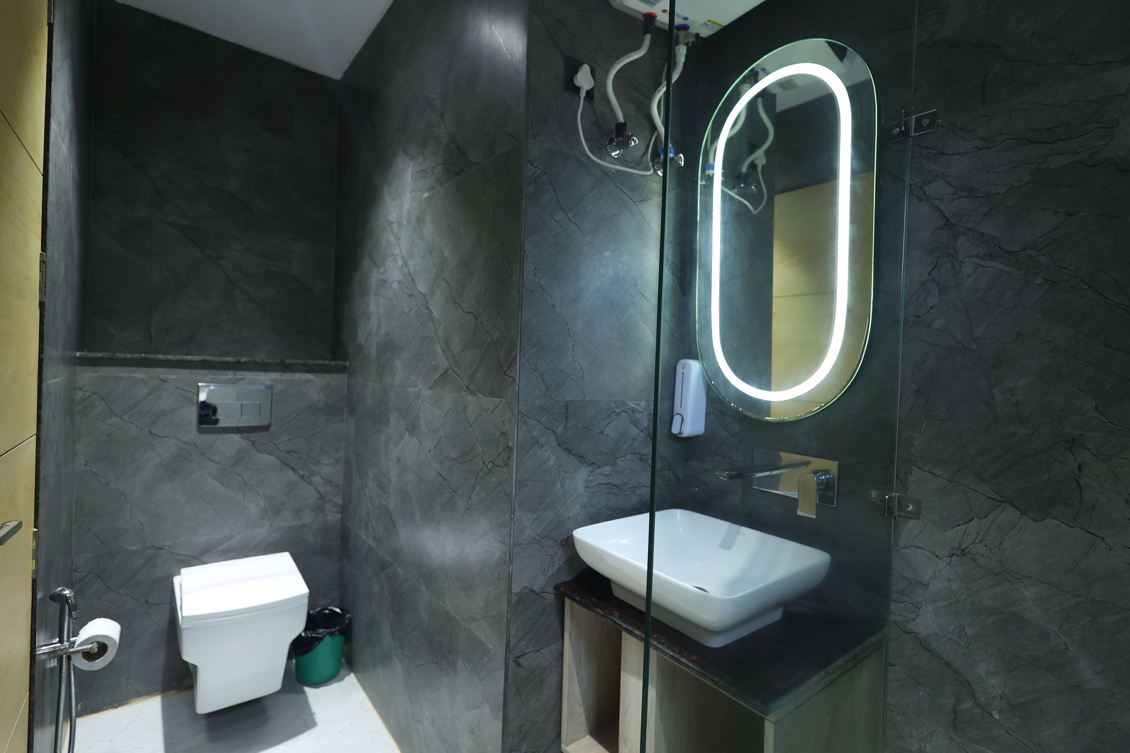 A modern bathroom with a glass-enclosed shower, a white sink, and a mirror with a built-in light.