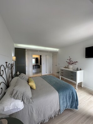 A modern bedroom with a large bed, a dresser, a vanity, and a television. - LUXURY DUPLEX IN FOZ WITH SEA VIEWS (Foz)
