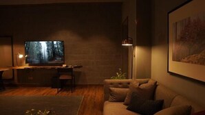 A cozy living room with a television, a sofa, a coffee table, and a lamp. - Byarsa Hotel Skardu (Skardu)
