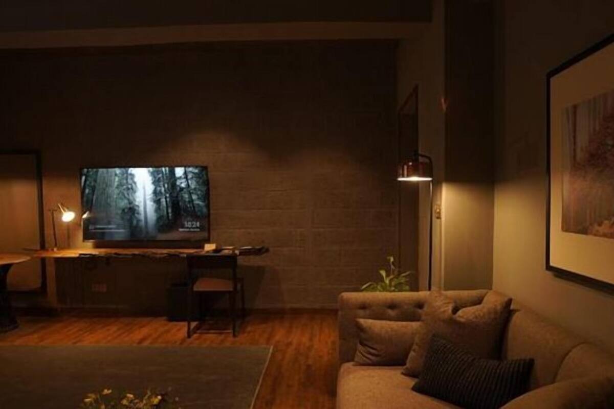 Uma sala de estar acolhedora com televisão, sofá, mesa de centro e abajur.
