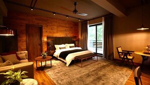 A modern bedroom with a large bed, a wooden accent wall, a dining area, and a view of the outdoors. - Byarsa Hotel Skardu (Skardu)
