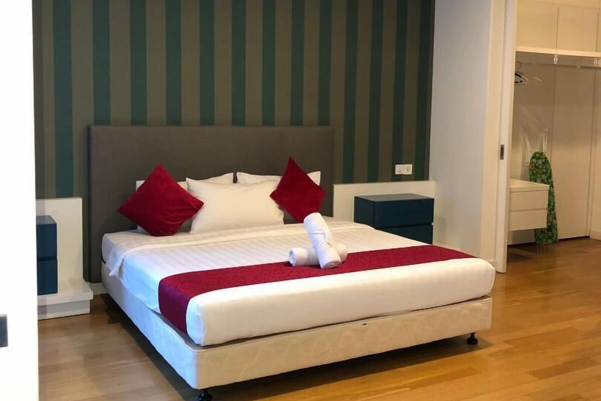 A modern bedroom with a large bed, striped wall, and wooden flooring.