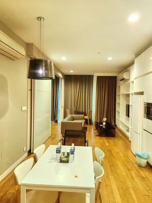 A modern hotel room with a dining area, a sofa, a TV, and a minibar. - Amazing Pool By Platinum Suites (Kuala Lumpur)