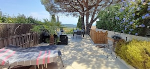 An outdoor patio area with a dining table and chairs, surrounded by a wooden fence and various plants. - Maison Tout Confort, Grande Terrasse vue Mer, Proche de St-tropez (La Croix Valmer)