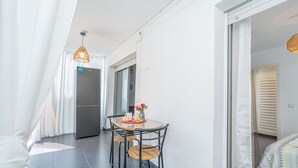 A modern kitchen with a dining area, featuring a table with chairs, a refrigerator, and a hanging light fixture.