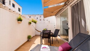 A small outdoor patio with a table and chairs, a hammock, and a lounge chair with cushions.