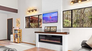 A living room with a fireplace, a television mounted on the wall, and a bookshelf.
